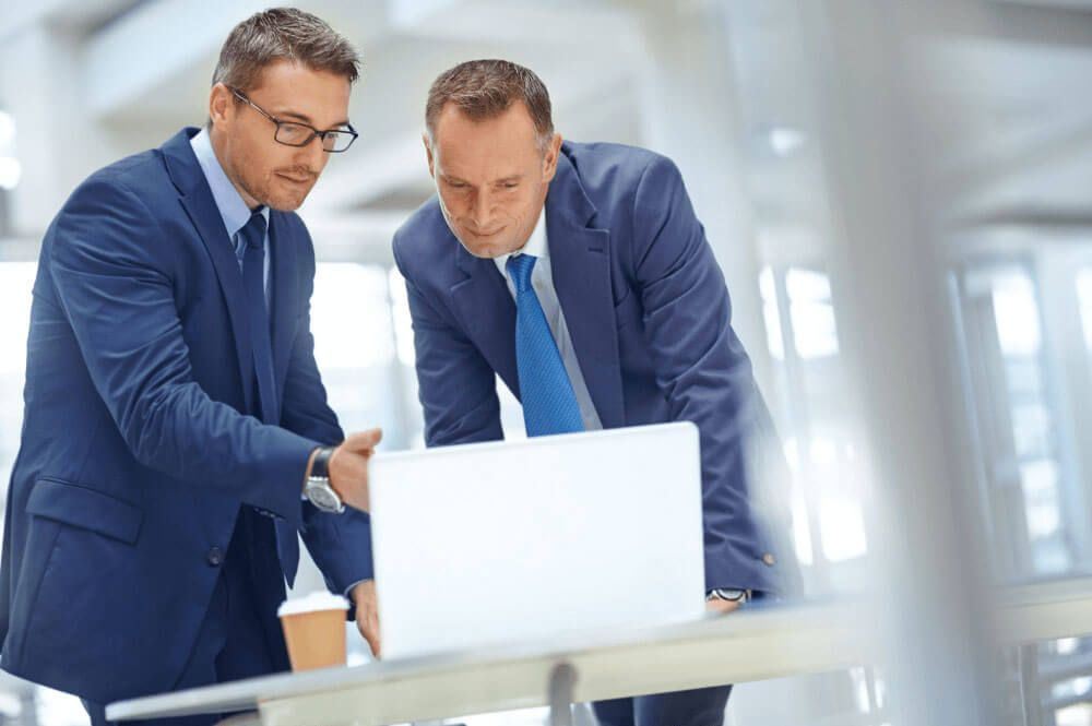 two business men reviewing a document on a laptop